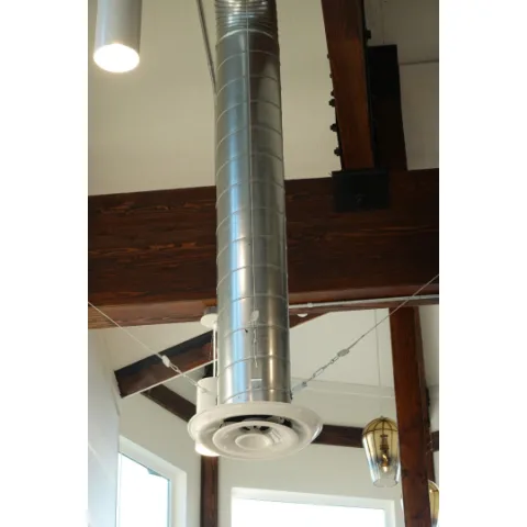 Round ceiling air outlet connected to a metal duct.