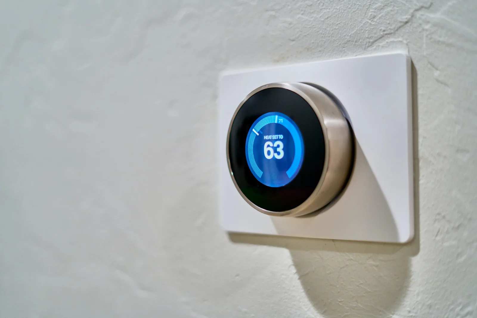 Round digital thermostat mounted on a wall.