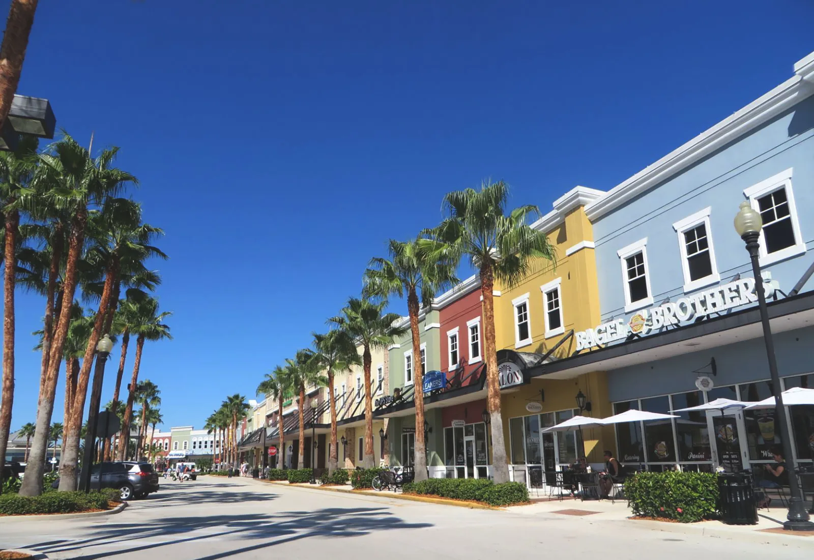 Palm-lined shopping street with colorful storefronts.